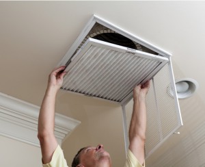 man changing furnace air filter in ceiling