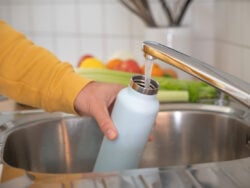 Man fills up reusable water bottle in the kitchen