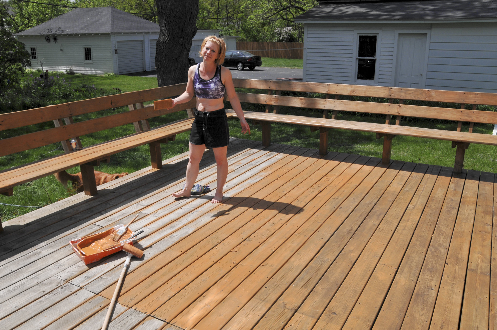 a woman painting her deck doing home upgrades