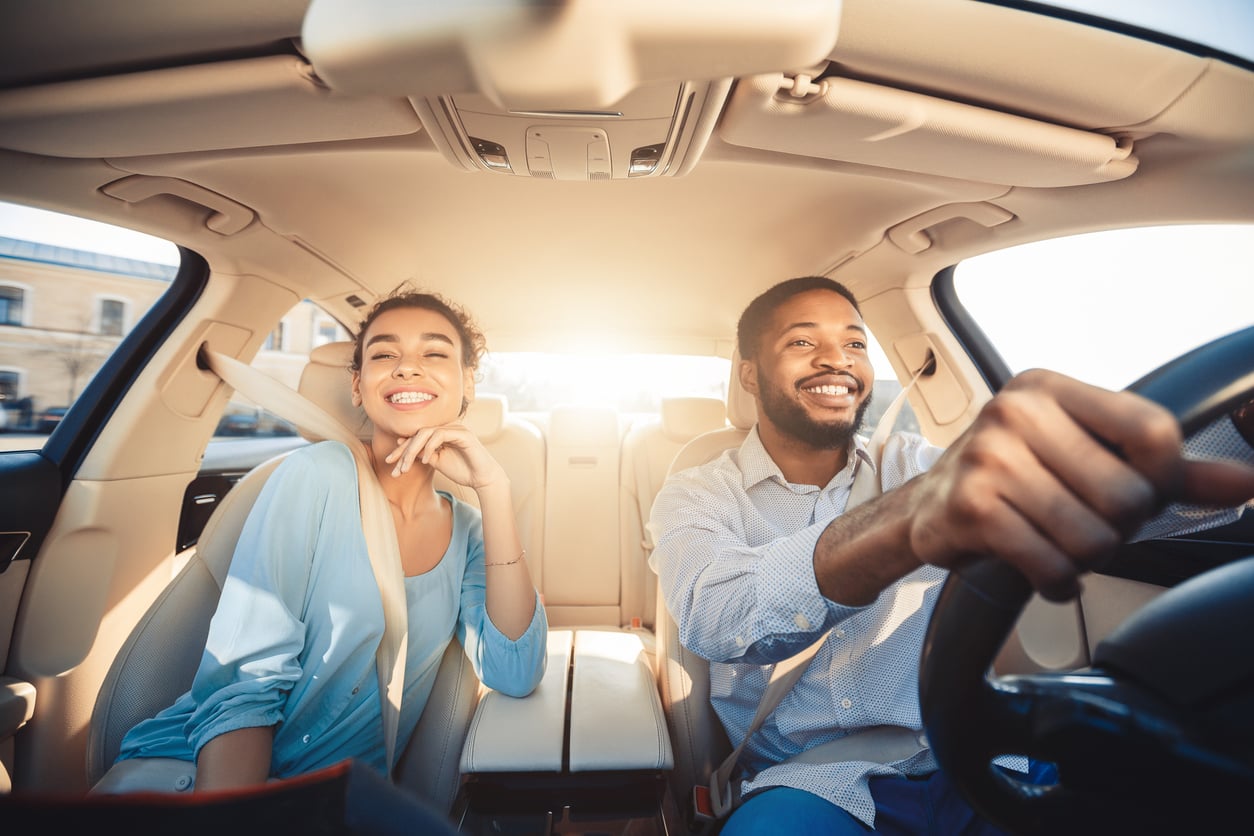 Enjoying travel. Excited african couple driving car and smiling, copy space because of their air filter for car