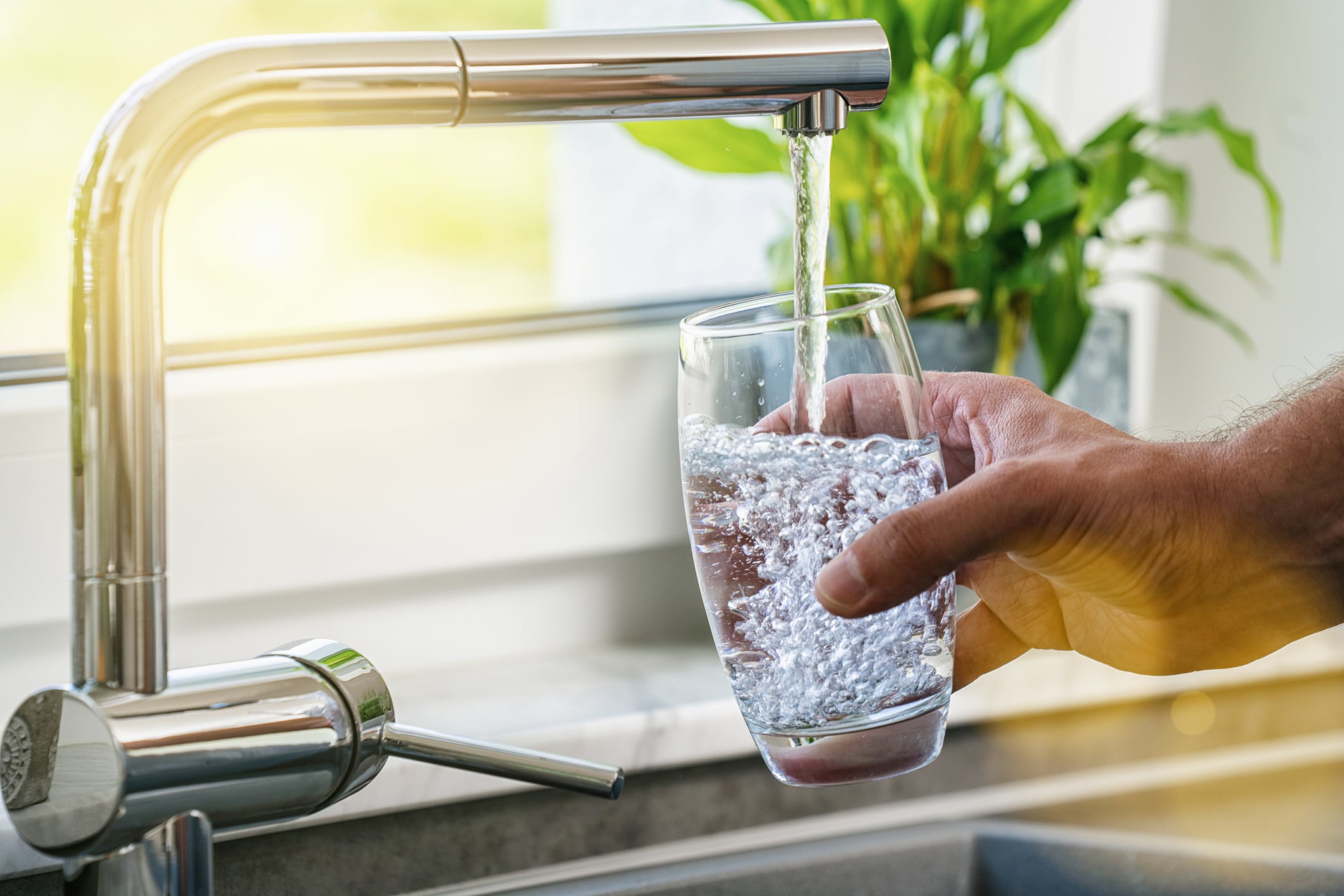 person filling up glass at the sink from reverse osmosis