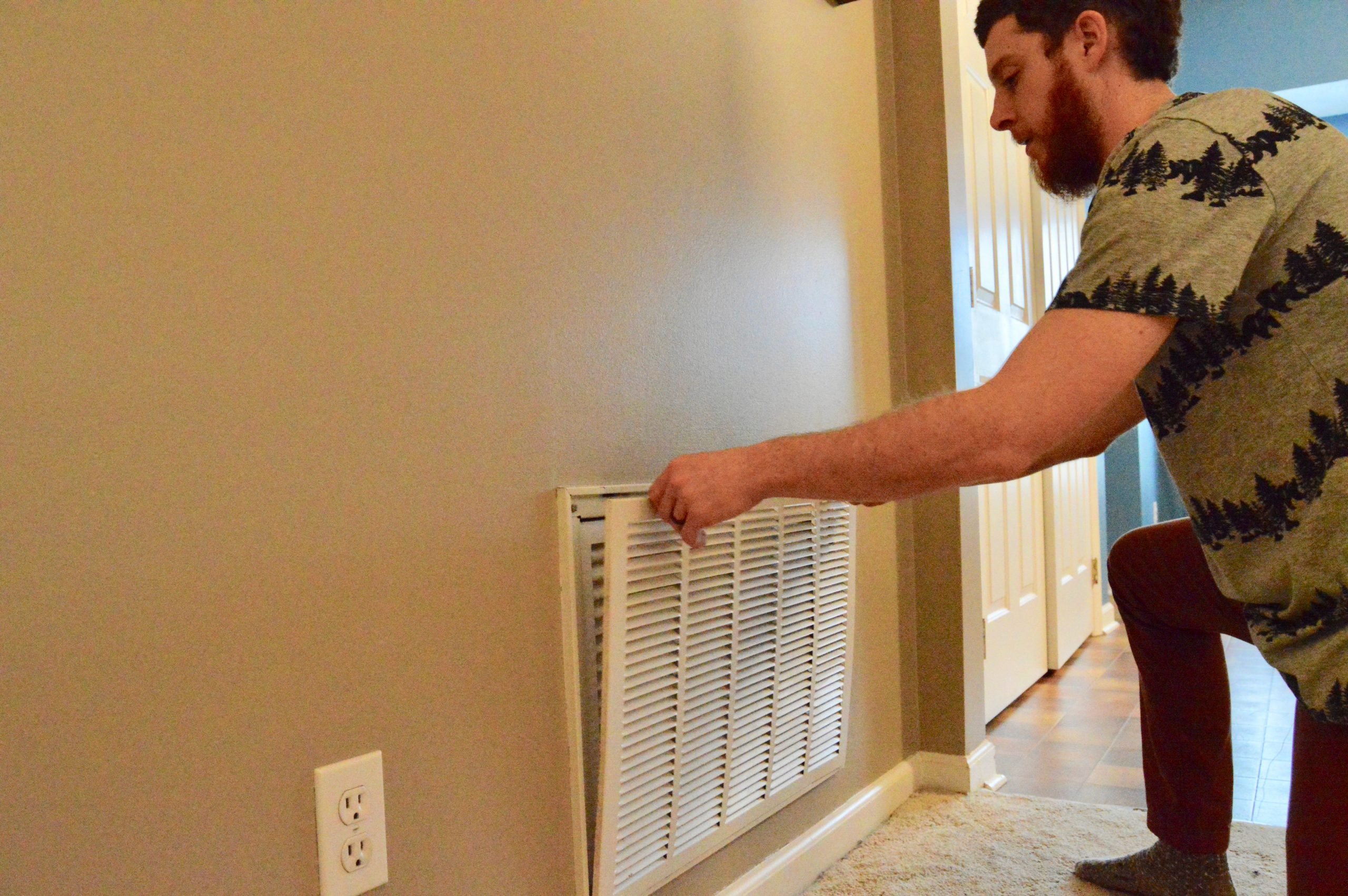 man changing HVAC filter in wall