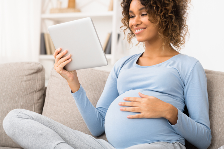 Pregnant woman reading something on a tablet