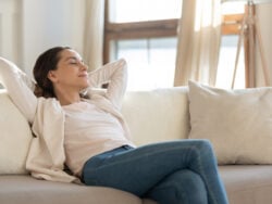Confident millennial female enjoying tranquility relaxing on sofa indoors