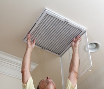 Older man replacing his MERV rated filter in the cieling