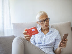 Woman checking the ingredient. Happy and cheerful senior woman holding pills in hand, using modern smartphone, searching information