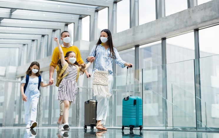 Family with two children going on holiday, wearing face masks at the airport.