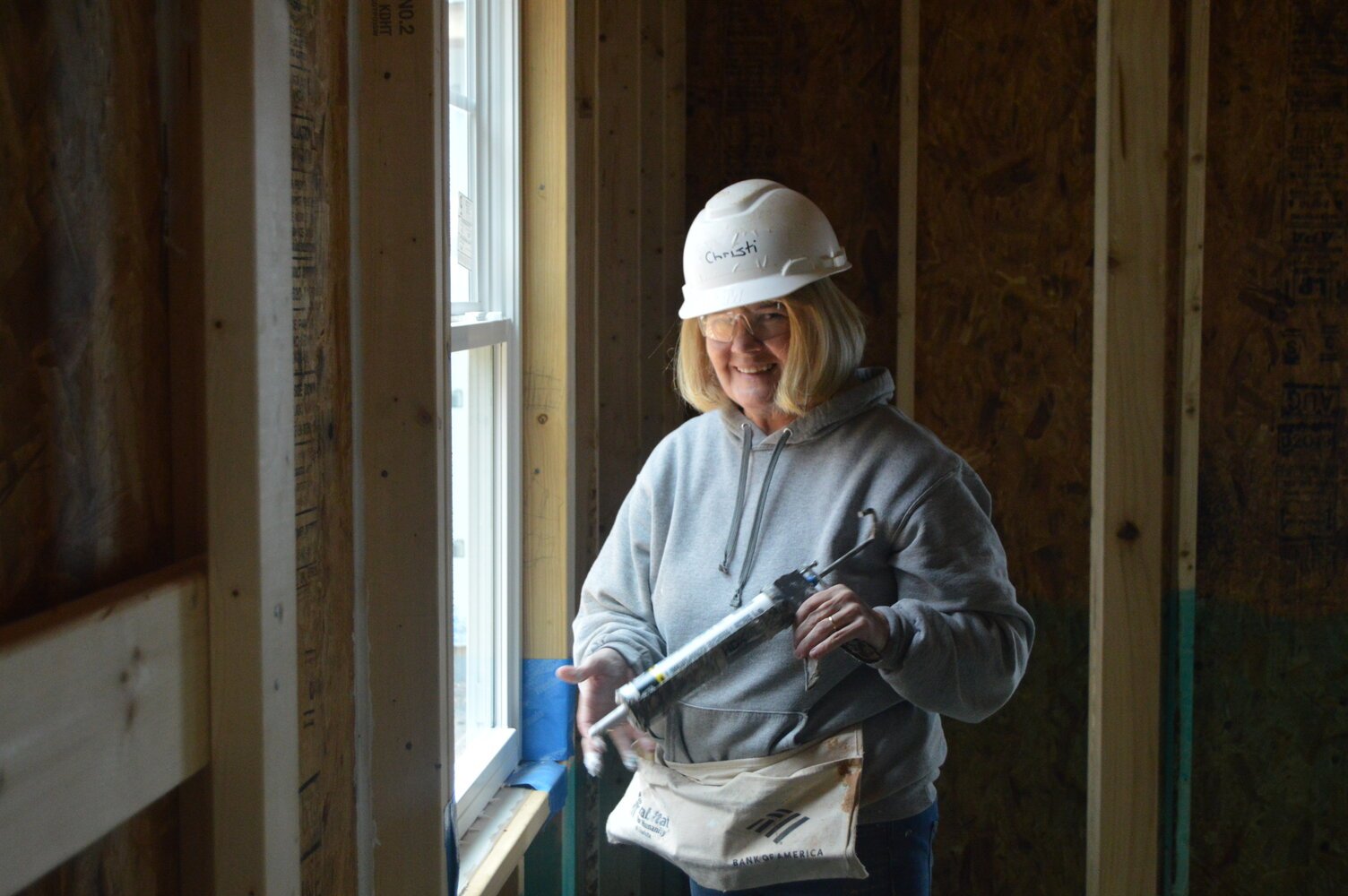 Filters Fast employee smiles while caulking window