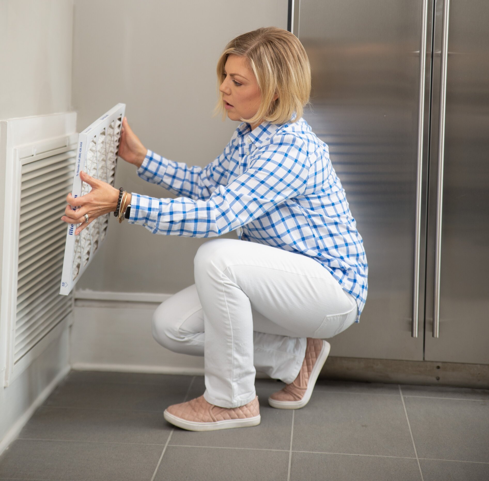 woman hold air filter in front of furnace grille to see if it fits