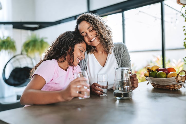 Mother and daughter drinking water together from a counter top water filter