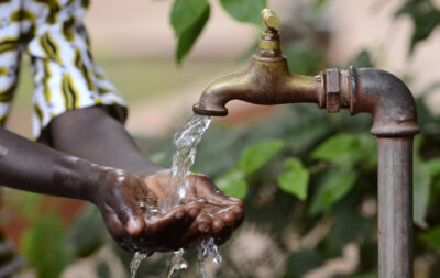 Hand of an African black boy with water pouring from a tap. Water scarcity or lack of safe drinking water is one of the world's leading problems affecting more than 1 billion people globally, meaning that one in every six people lacks access to safe drinking water. This affects people and especially children in Africa.