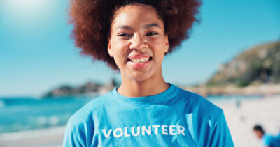 Volunteer, happy and portrait of African woman on beach for cleaning dirt, plastic and litter for ocean. Community service, charity and person for environmental care, recycling and climate change